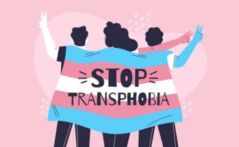 An illustration of 3 people holding the trans flag with the message "Stop Transphobia" on it